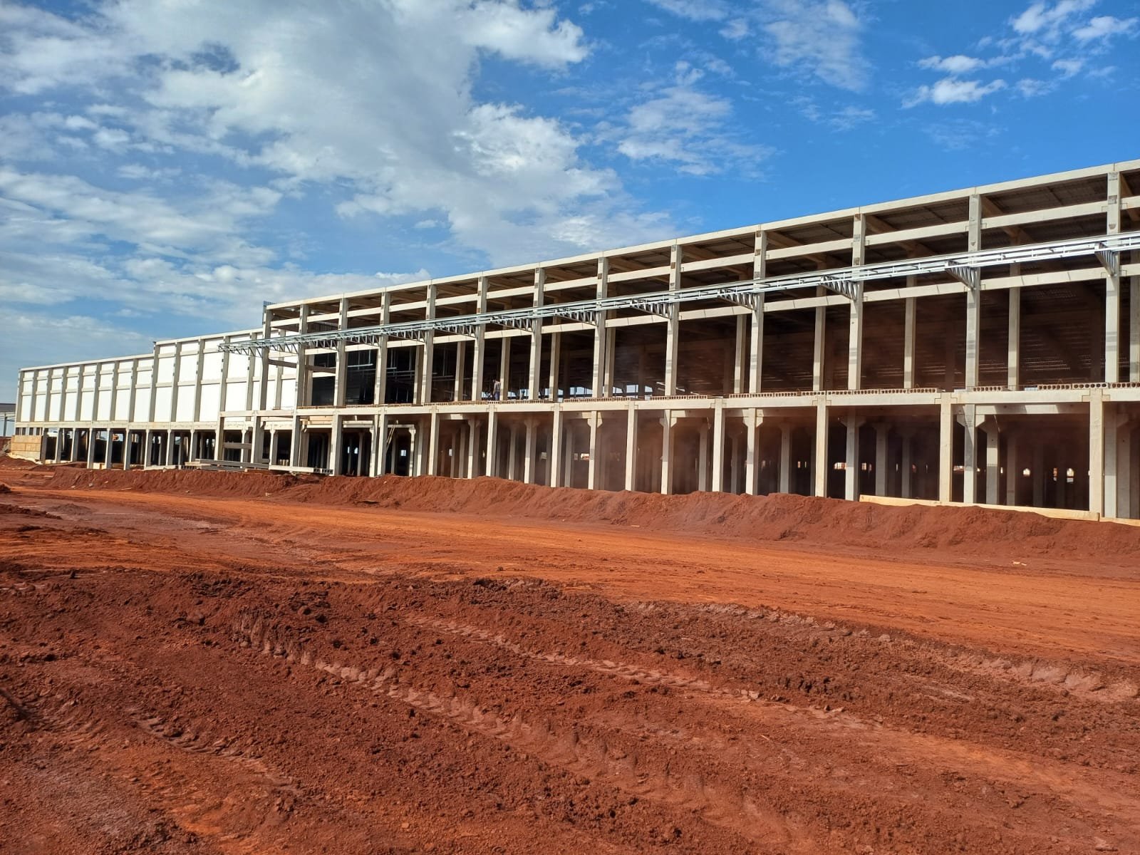 Vista aérea de grande obra com estrutura pré-moldada e terra vermelha